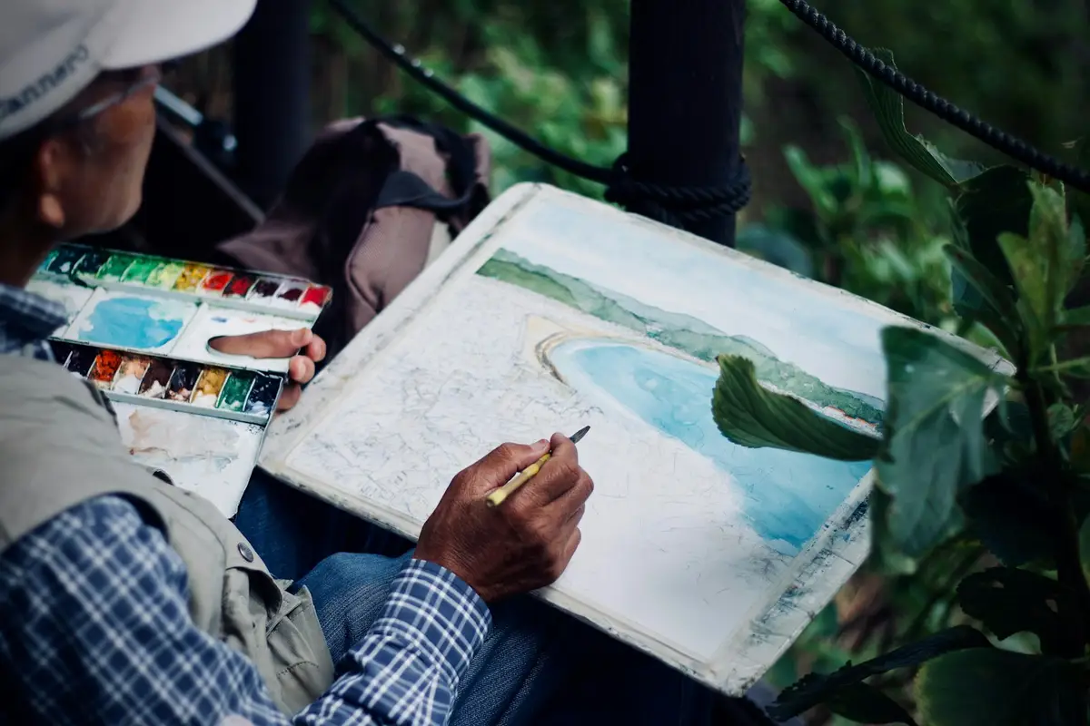 Pessoa a pintar uma paisagem de costa com aguarelas ao ar livre – Totenart